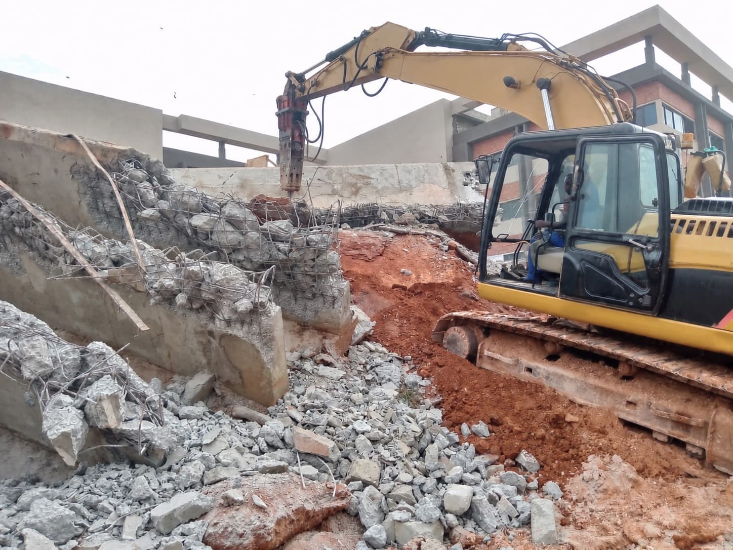 Excavator removing reinforced concrete from an existing structure