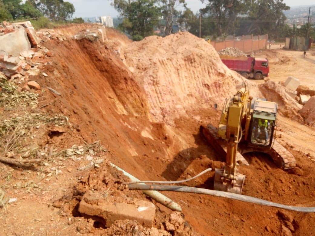 Excavator forming a deep cut through red soil
