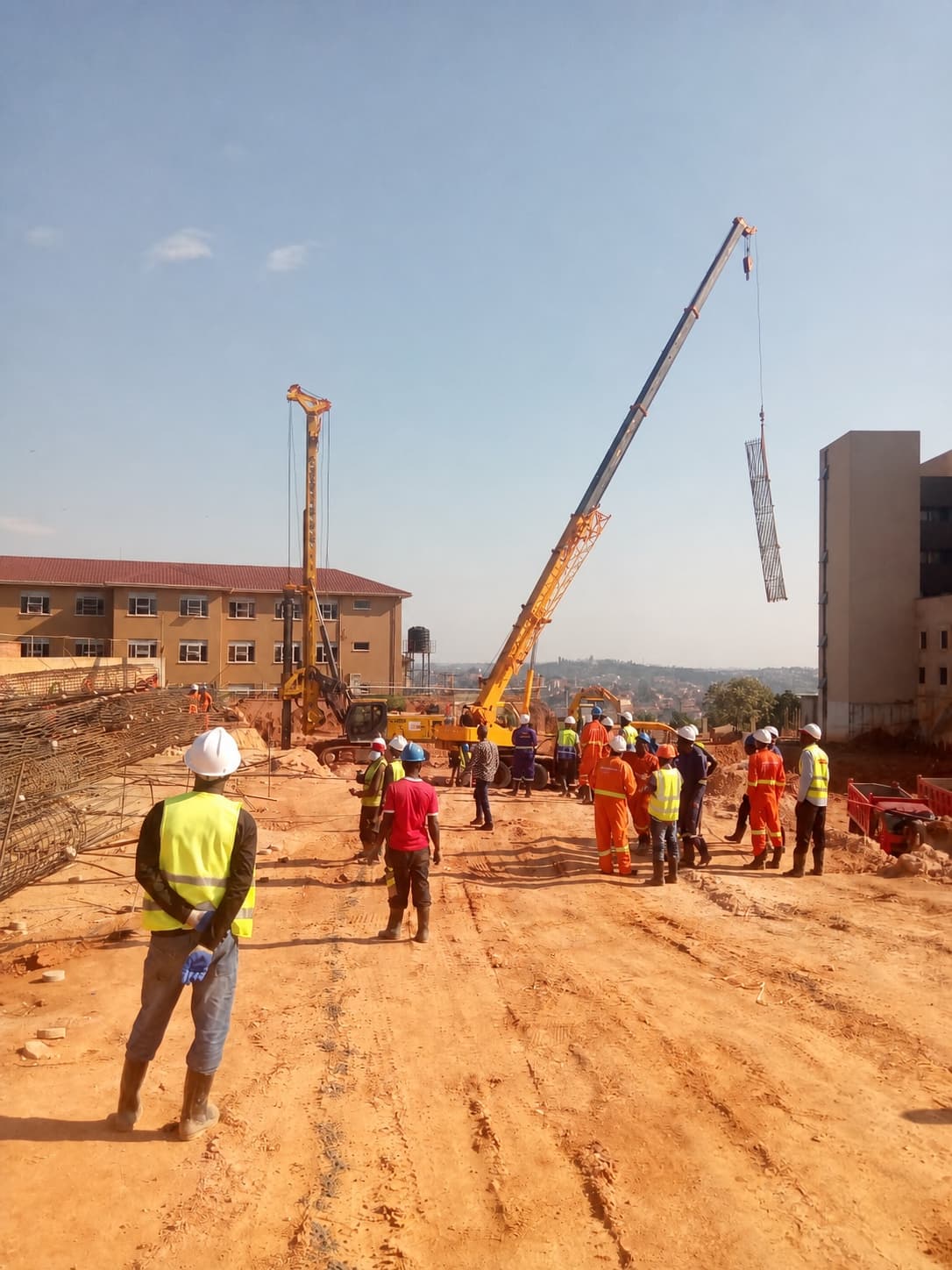 Crane lifting a reinforcement cage beside a piling rig