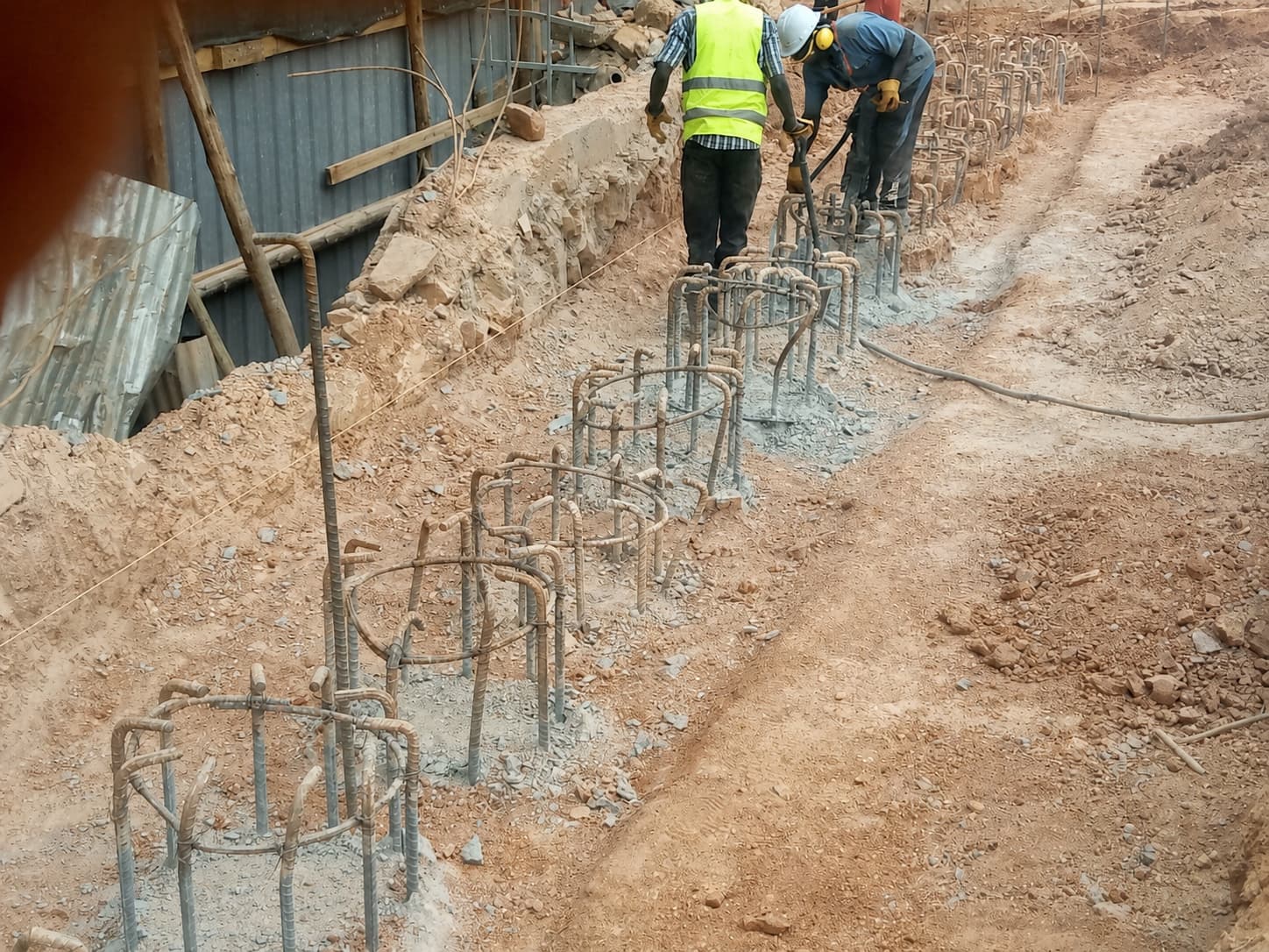 Workers completing a line of reinforced pile starters